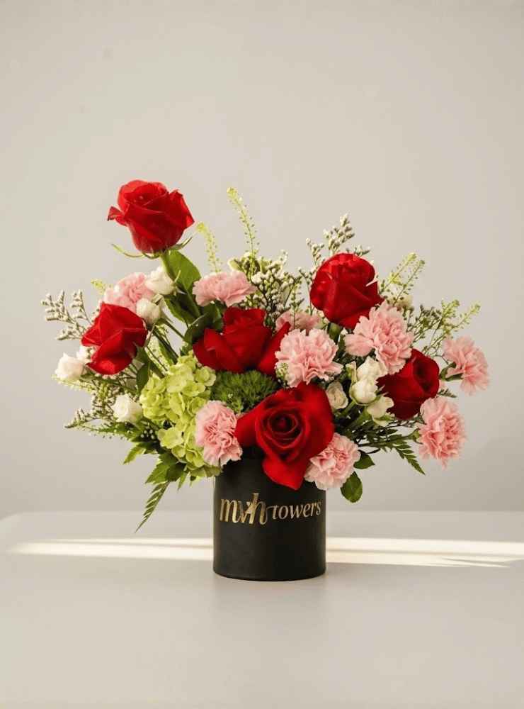 Velvet Harmony Arreglo floral romántico con rosas rojas, flores rosadas y follaje verde, ideal para expresar amor, pasión y ternura.